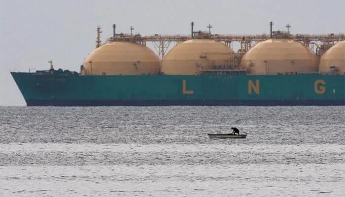 This representational file photo shows a fisherman standing in his boat as a liquid natural gas tanker (LNG) passes the coast near Havana. — Reuters