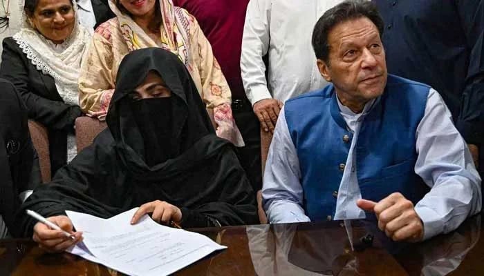 Former prime minister Imran Khan (right), along with his wife Bushra Bibi, signs surety bonds for bail in various cases, at the registrars office in the Lahore High Court on July 17, 2023. — AFP