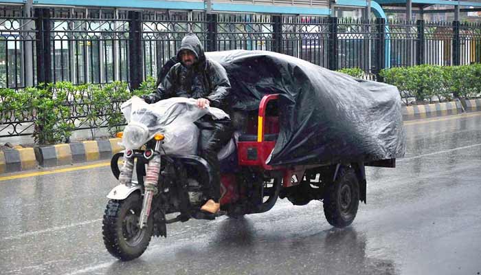 A supplier drives a loader vehicle covered with polythene sheet to protect from rain that experiencing in Peshawar. — APP/file