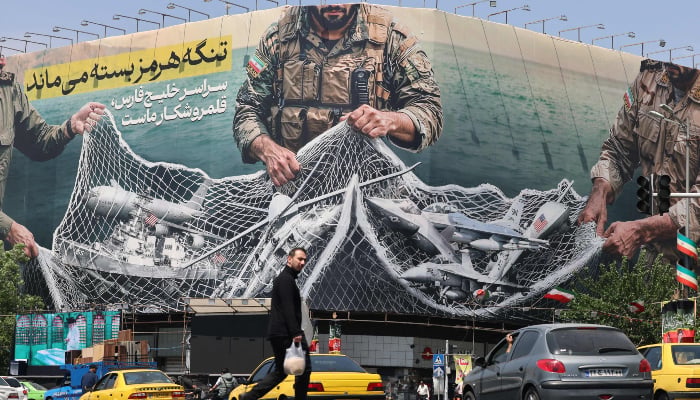 Vehicles drive past a giant billboard reading The Strait of Hormuz remains closed at the Revolution Square in Tehran on April 28, 2026. — AFP