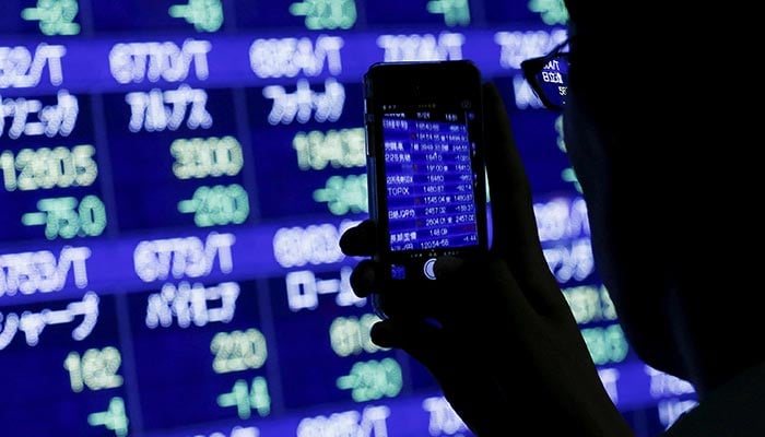 A man uses his phone to take pictures of market indices at a stock quotation board outside a brokerage in Tokyo, August 24, 2015. — Reuters