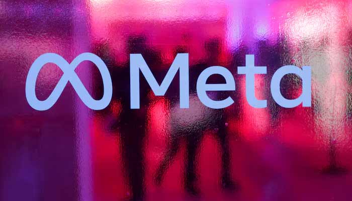 People walk behind a logo of Meta Platforms company, during a conference in Mumbai, India. — Reuters/File