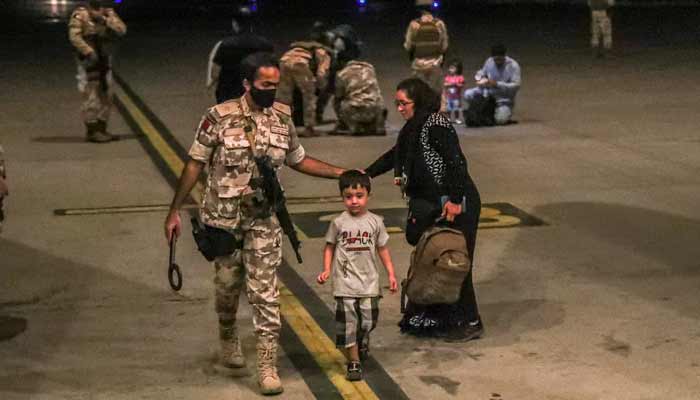 A member of the Qatar Air force walks next to a boy evacuated from Afghanistan, at Al-Udeid airbase in Doha. — Reuters/File