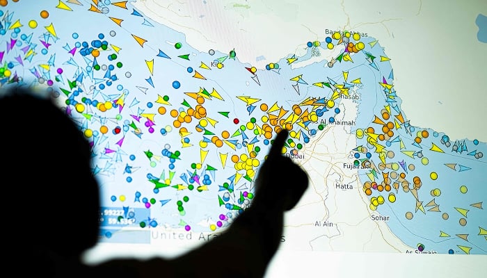 A photo illustration taken in Nicosia on May 4, 2026, shows a person in front of a large screen displaying vessel movements in the Strait of Hormuz on a ship-tracking website. — AFP
