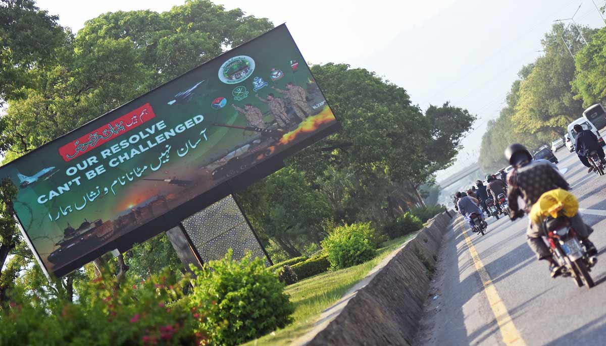 Commuters move past a roadside digital billboard at a green belt along Islamabad Expressway, in the Federal Capital as Pakistan is commemorating the first anniversary of Operation Bunyan-un-Marsoos — Online