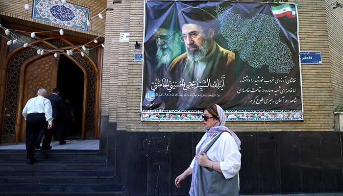 An Iranian woman walks a mosque decorated with a banner depicting Irans current leader Ayatollah Mojtaba Khamenei, in the capital Tehran on May 9, 2026. — AFP