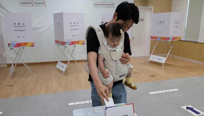 A voter carrying a baby casts his ballot at a polling station during the presidential election in Seoul, South Korea, June 3, 2025. — Reuters/File