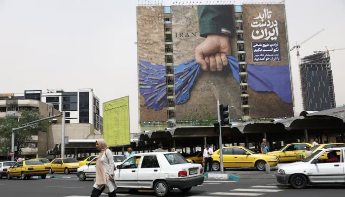 People walk past a billboard about the Strait of Hormuz in Tehran, Iran, May 4, 2026. — Reuters