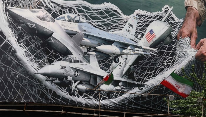 A giant billboard depicting Iranian troops using a net to catch US combat aircraft is seen at the Revolution Square in Tehran on April 28, 2026. — AFP