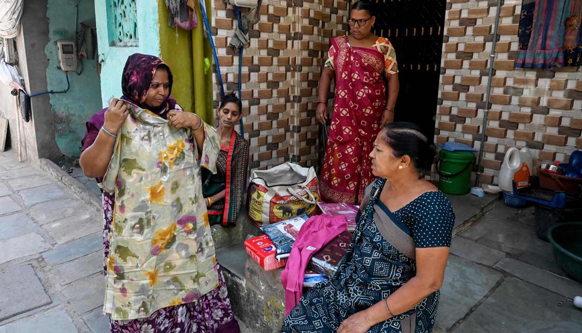 Lata Solanki (L), a clothes seller and policyholder of a heat insurance scheme, conducting a door-to-door sales in Ahmedabad. Solanki used to face a devastating choice when Indias summer heat hit dangerous levels. — AFP