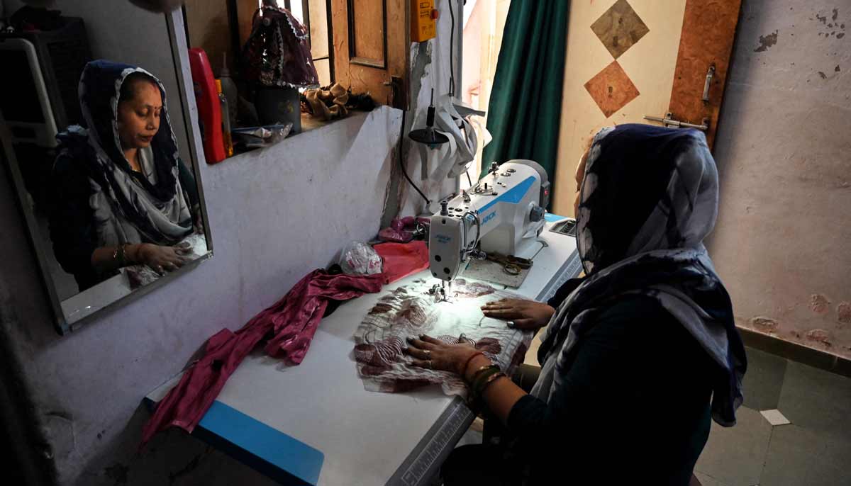 Rakhi Gulshan Singh, a seamstress and policyholder of a heat insurance scheme, working inside her single-room rented house in Ahmedabad.— AFP