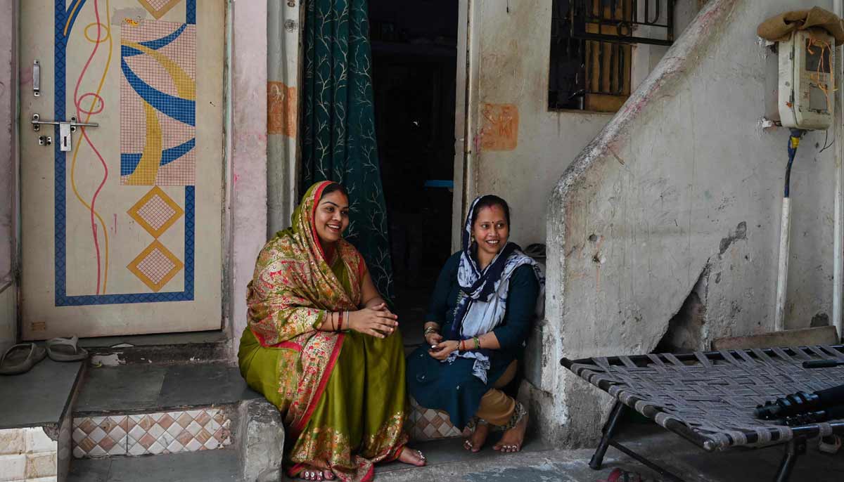 Rakhi Gulshan Singh (R), a seamstress and policyholder of a heat insurance scheme, sitting outside her single-room rented house in Ahmedabad.— AFP