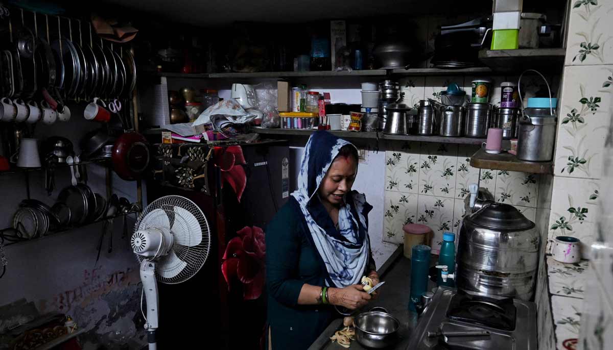 Rakhi Gulshan Singh, a seamstress and policyholder of a heat insurance scheme, preparing a meal inside her single-room rented house in Ahmedabad.— AFP