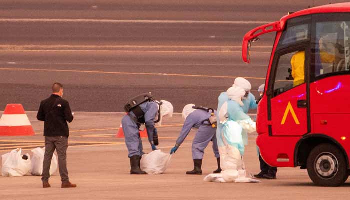 Persons wearing hazmat suits are pictured as passengers board a plane bound for US carrying passengers evacuated from the Dutch flagged hantavirus-stricken cruise ship MV Hondius at the Tenerife Sur-Reina Sofia airport on the island of Tenerife in Spain´s Canary Islands on May 10, 2026.— AFP