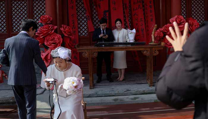 Newlywed couples pose for pictures at the Huguo Guanyin Temple, an outdoor marriage registration site in Beijing, China, October 28, 2025.— Reuters