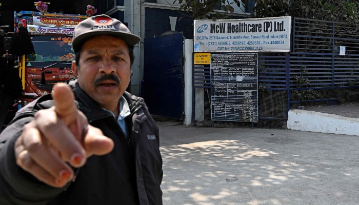 This photograph, taken on January 19, 2026, shows a security guard pointing to a camera outside Indian pharmaceutical firm McW Healthcare´s manufacturing plant in Indore, India. — AFP