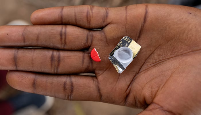 A drug addict holds half of a red Tapentadol based tablet in their palm in Abuja on February 24, 2026. — AFP