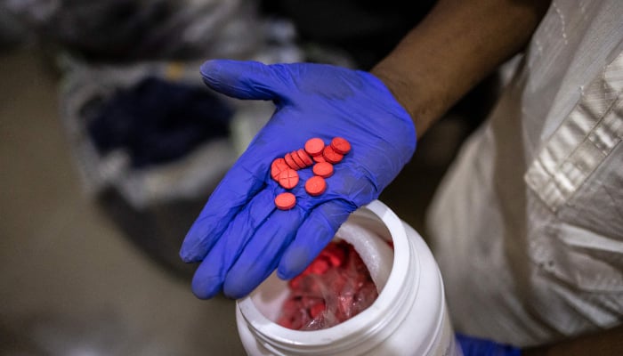 An officer holds seized red Tapentadol tablets at the National Drug Law Enforcement Agency (NDLEA) facility in Lagos, on February 19, 2026. — AFP