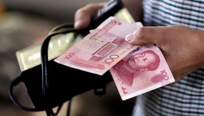 A customer holds a 100 Yuan note at a market in Beijing, August 12, 2015. — Reuters