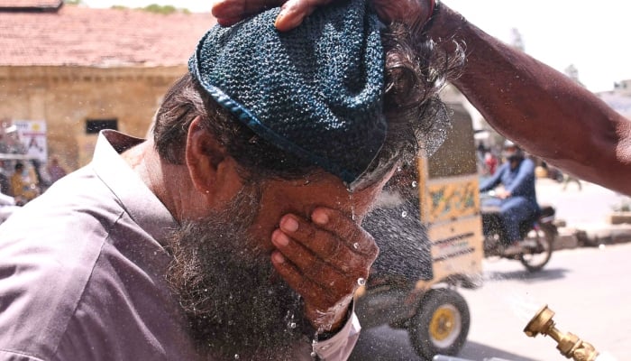 A volunteer sprays water on a man to cool off on a hot summer day in Karachi, May 4, 2026. — Online
