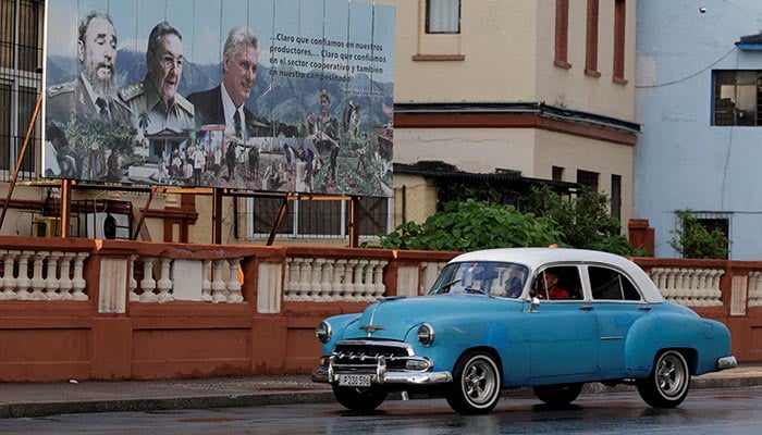 A vintage car passes by images of late Cuban President Fidel Castro, Cubas former President Raul Castro and Cubas President Miguel Diaz-Canel displayed on a billboard in Havana, Cuba, May 15, 2026. — Reuters