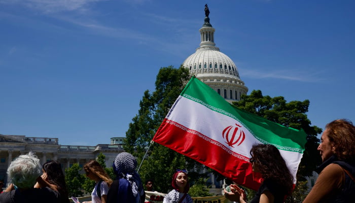 A demonstrator carries an Iranian flag as people gather near the US Capitol while participating in a Nakba solidarity bike ride from Dupont Circle to the US Capitol in Washington, DC, on May 16, 2026. — AFP
