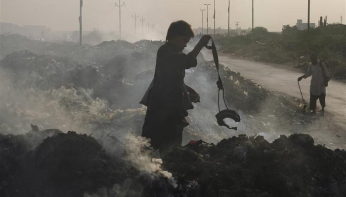 A boy holds a magnet as he and another search for recyclables along a roadside dump in Karachi, October 26, 2011. — Reuters