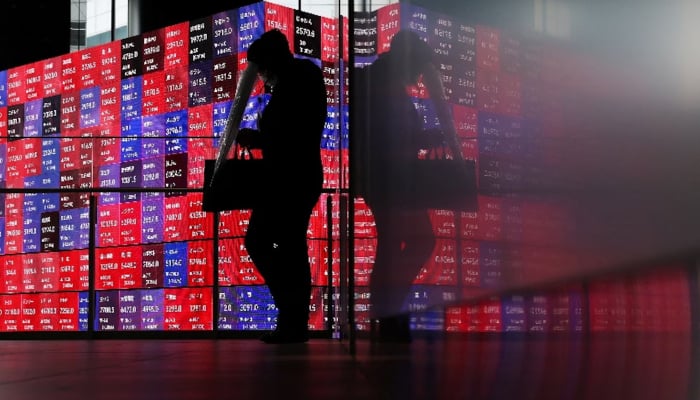 A man walks in front of an electronic screen displaying Japans Nikkei stock prices quotation board inside a conference hall in Tokyo, Japan, April 27, 2026. — AFP