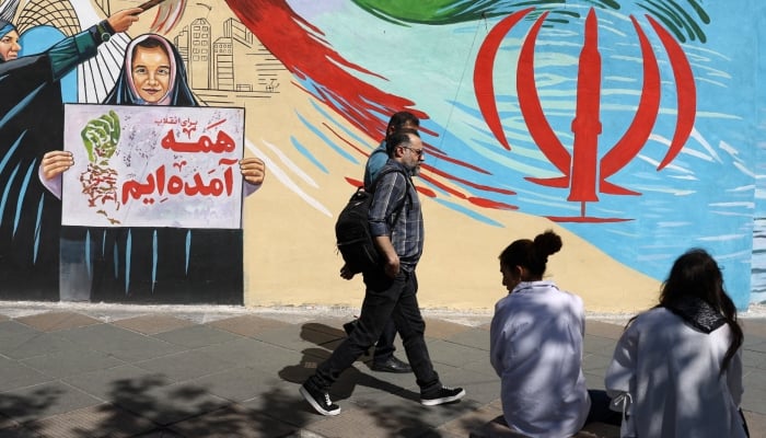 People walk next to a mural on a street in Tehran, Iran, May 18, 2026. — Reuters