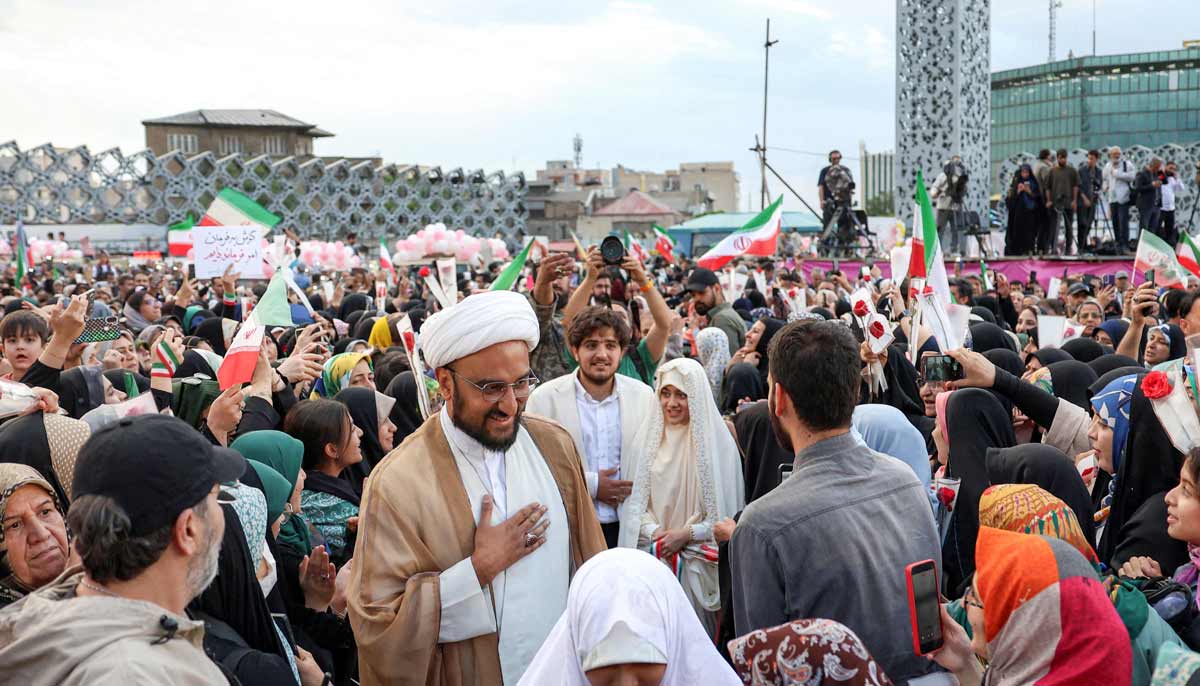 A Shia Muslim cleric arrives as a groom with his bride with other couples at a public mass wedding ceremony at Imam Hossein Square in Tehran on May 18, 2026.— AFP