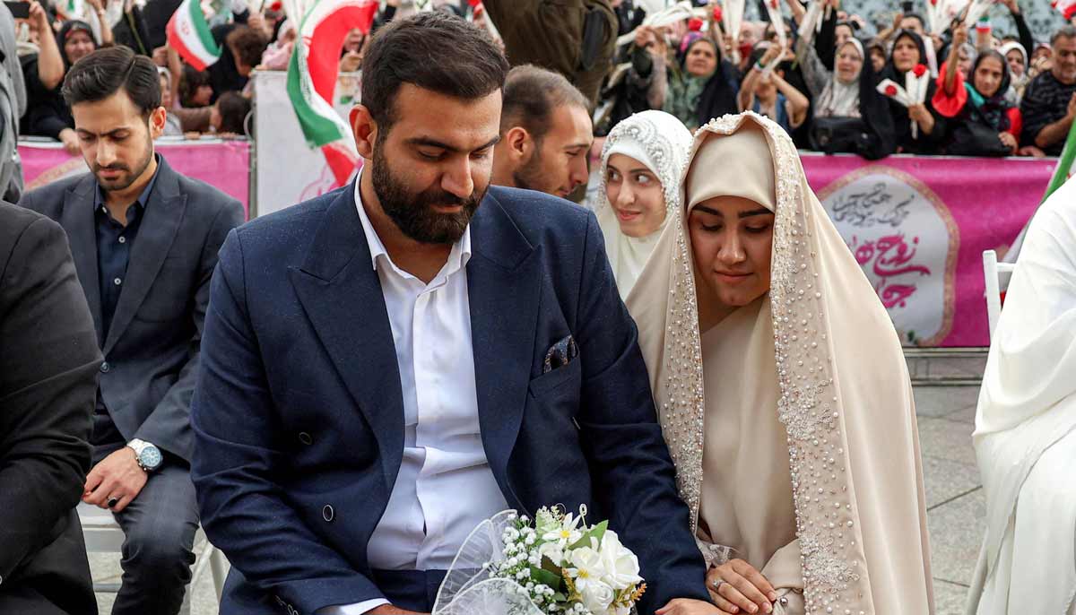 A bride and groom couple attends a public mass wedding ceremony at Imam Hossein Square in Tehran on May 18, 2026.— AFP