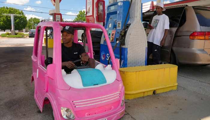 Mali Hightower, 30, poses with what he describes as a self-created gas saver, a pink Power Wheels Barbie Dream Camper, at a gas station in Ellenwood, Georgia, US, May 18, 2026.— Reuters