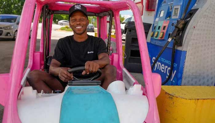 Mali Hightower, 30, poses with what he describes as a self-created gas saver, a pink Power Wheels Barbie Dream Camper, at a gas station in Ellenwood, Georgia, US, May 18, 2026. — Reuters