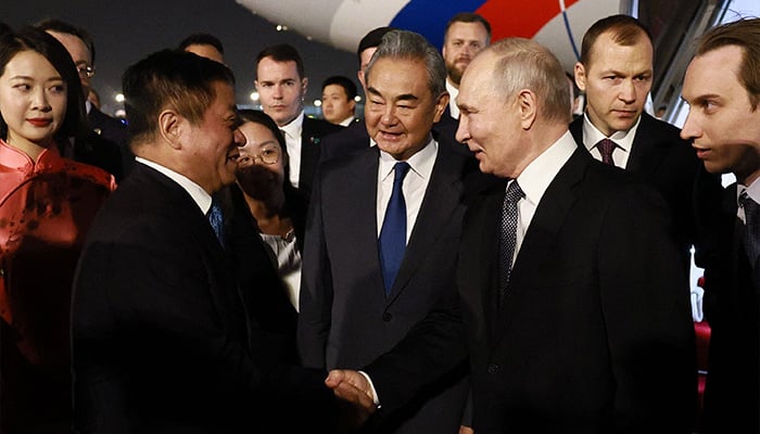 In this pool photograph distributed by the Russian state agency Sputnik, Russias President Vladimir Putin is welcomed by Chinese Foreign Minister Wang Yi and other officials upon his arrival at Beijing Capital Airport in Beijing late on May 19, 2026. — AFP