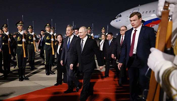 In this pool photograph distributed by the Russian state agency Sputnik, Russias President Vladimir Putin is welcomed by Chinese Foreign Minister Wang Yi upon his arrival at Beijing Capital Airport in Beijing late on May 19, 2026. — AFP