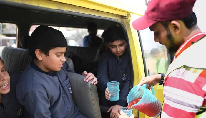A volunteer serves juice to children on the roadside during a heatwave in Karachi. May 6, 2026. — INP