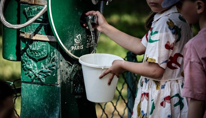 Children fill a bucket with water at a public fountain in the Montparnasse district of Paris on May 25, 2026, as French weather service Meteo-France placed the capital under yellow alert amid an exceptionally early heatwave, with temperatures forecast to reach 35°C across the region. — AFP