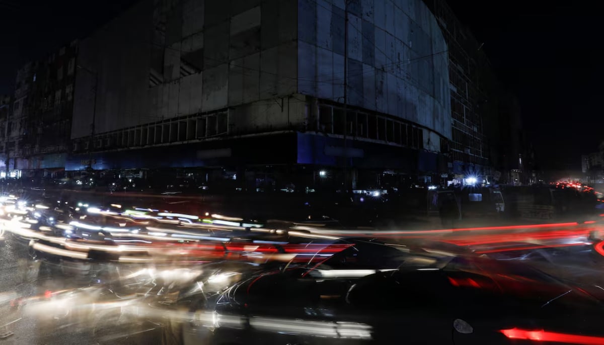 Vehicle lights cause light streaks on the road along a market during a power breakdown in Karachi. — Reuters