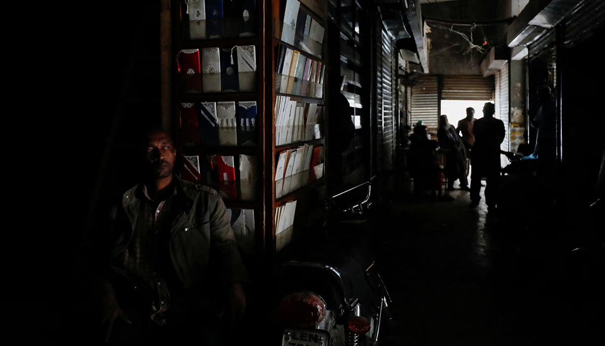 A man sits outside his shop during a power breakdown in Karachi. — Reuters