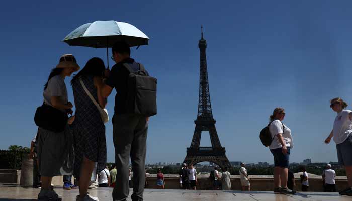 People shelter under an umbrella near the Eiffel Tower after temperatures reached up to 34 degrees during a period of hot weather in Paris, France, May 26, 2026.— Reuters