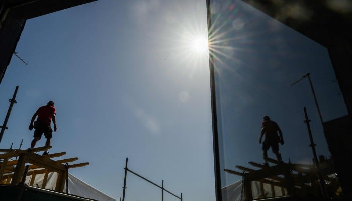 A carpenter works on a rooftop during a hot sunny day in Nantes, western France, on May 27, 2026, as a heatwave hits France. — AFP