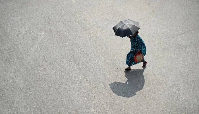 A pedestrian carries an umbrella on a hot day in Chennai. — AFP