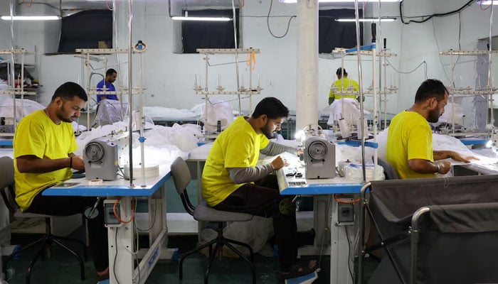 A representational image of workers in a garment factory stitching clothes. — Reuters/File