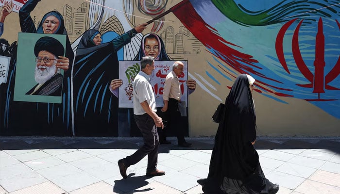 People walk on a street near a mural featuring an image of the late Supreme Leader of Iran, Ayatollah Ali Khamenei, in Tehran, Iran, June 1, 2026. — Reuters