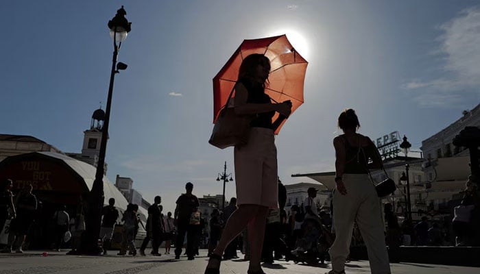 A woman with an umbrella walks at Plaza Puerta del Sol during a spring heatwave in Madrid, Spain. — Reuters/File