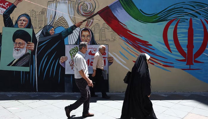 People walk on a street near a mural featuring an image of the late Supreme Leader of Iran, Ayatollah Ali Khamenei, in Tehran, Iran, June 1, 2026. — Reuters