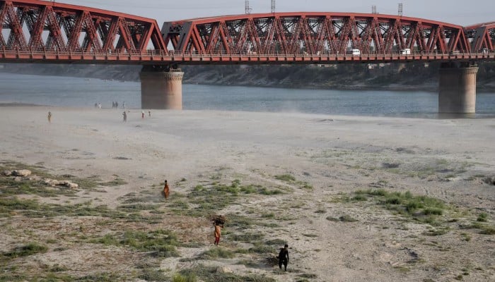 People walk on the dry riverbed of the Indus River in Hyderabad, April 24, 2025. — Reuters