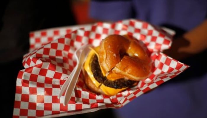 A boy holds a hamburger made with a doughnut bun at the Los Angeles County Fair in Pomona, California September 4, 2013. — Reuters