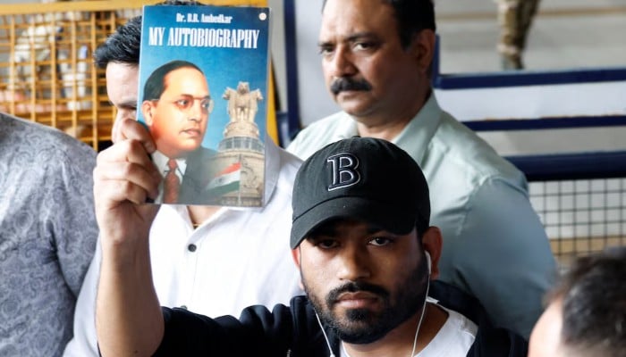 Abhijeet Dipke, head of the Cockroach Janta Party (CJP), holds a copy of My Autobiography by Dr BR Ambedkar as he leaves an airport in New Delhi, India, June 6, 2026. — Reuters