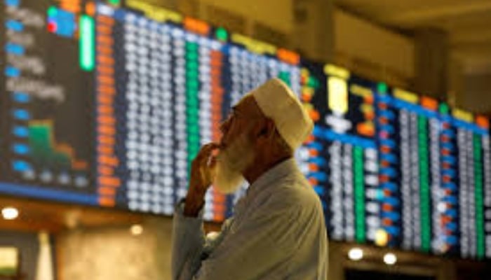 A stock broker reacts while monitoring the market on the electronic board displaying share prices during trading session at the Pakistan Stock Exchange, in Karachi, on July 3, 2023. — Reuters